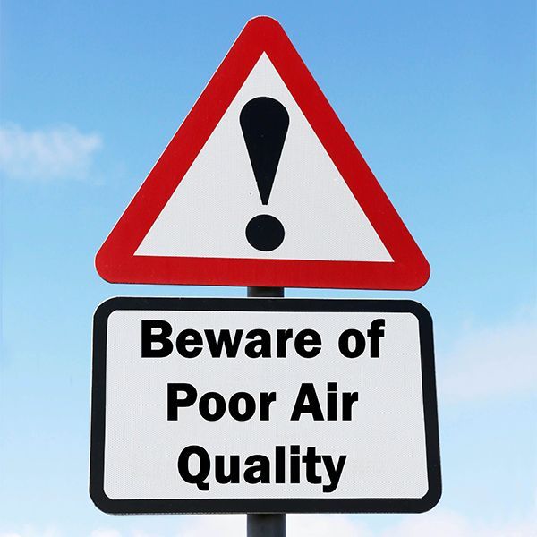 Warning sign with exclamation mark and text “Beware of Poor Air Quality” on a blue sky background