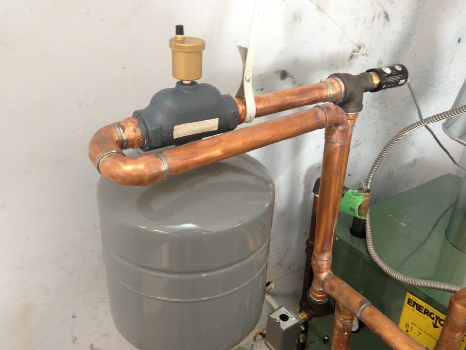 Copper plumbing pipes and a valve mounted above a gray water heater in a utility area