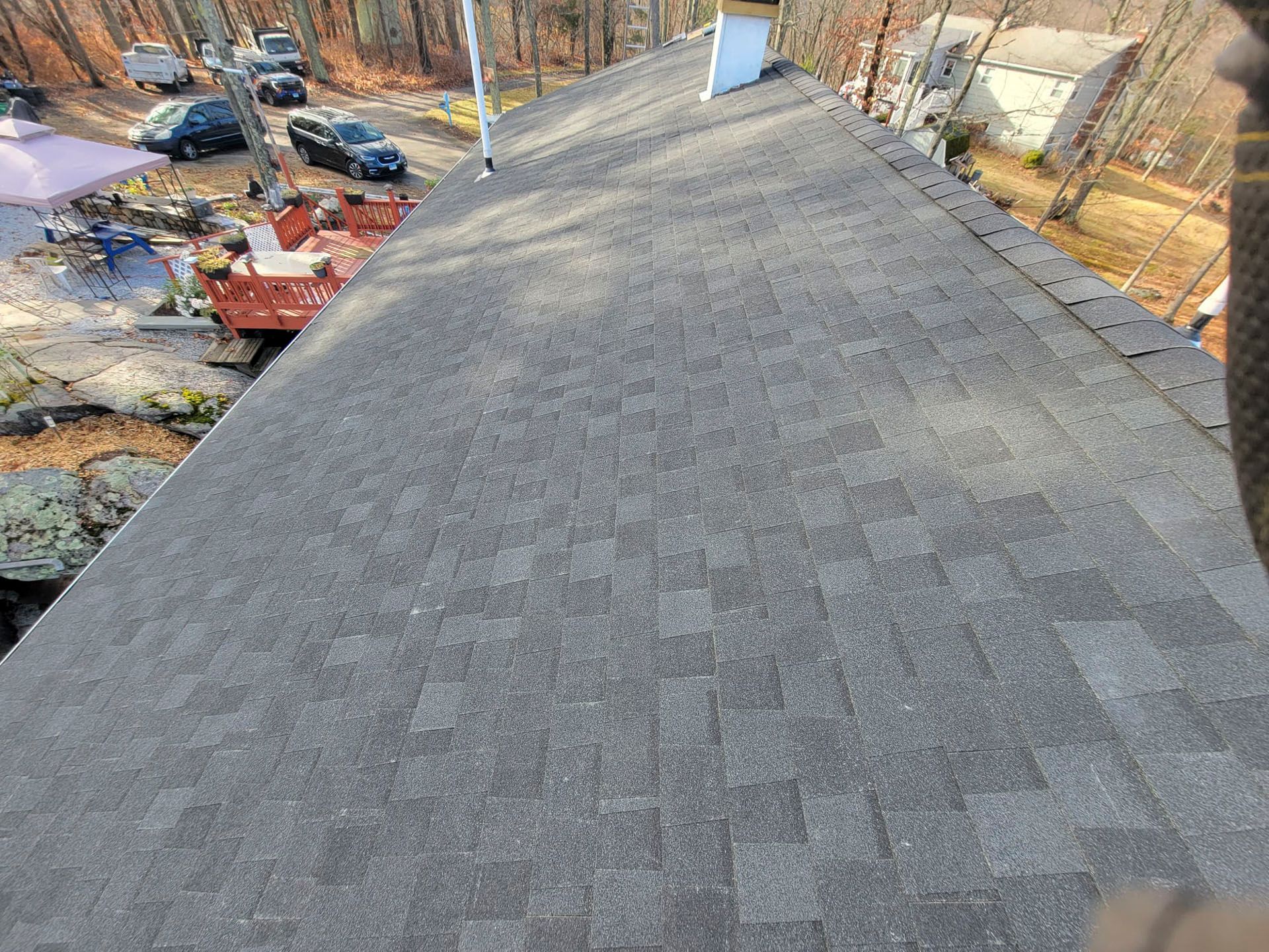 Gray shingled roof viewed from above, with trees and yard visible along the sides