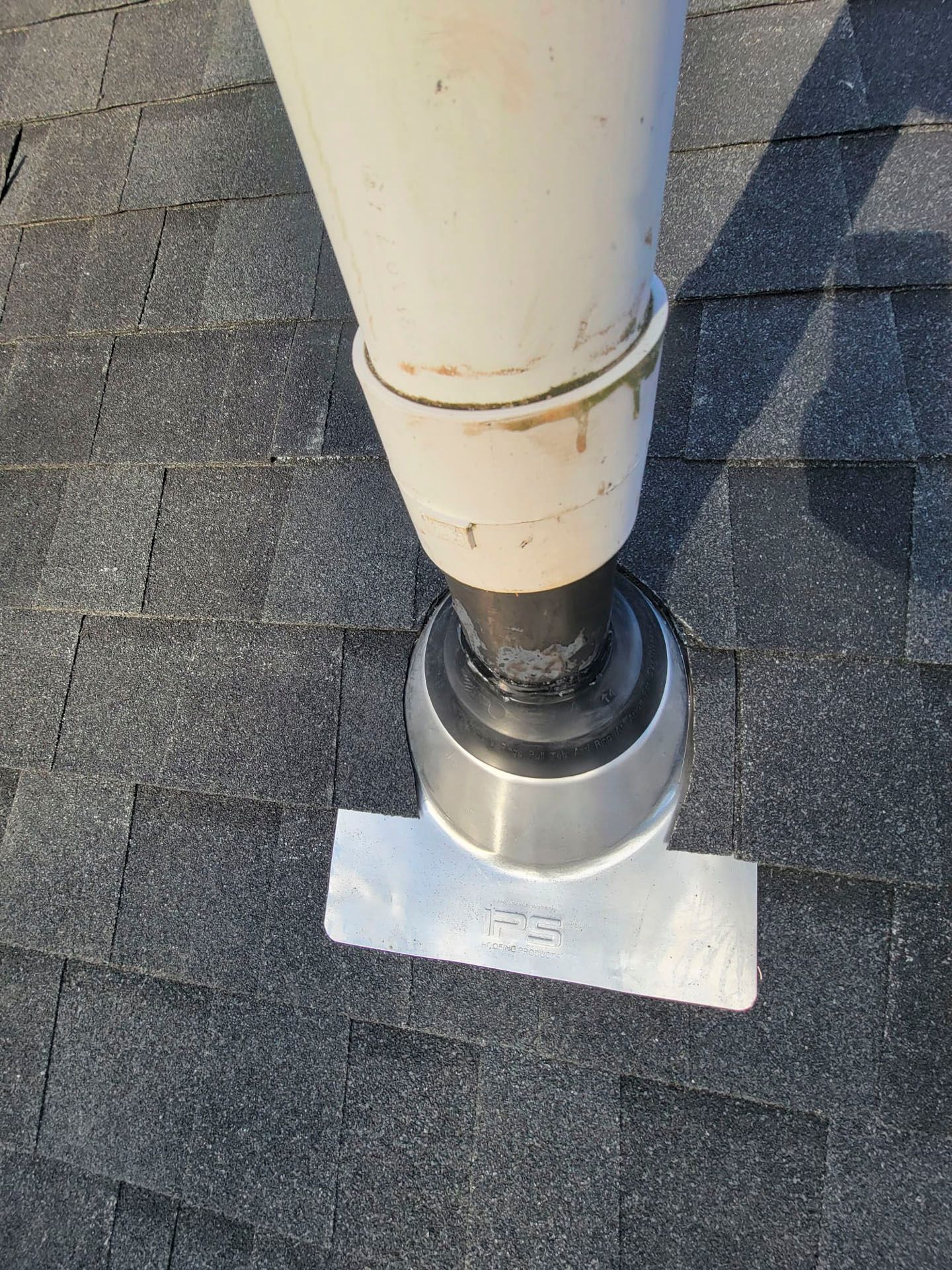 Roof vent pipe with flashing and sealant on gray shingle shingles