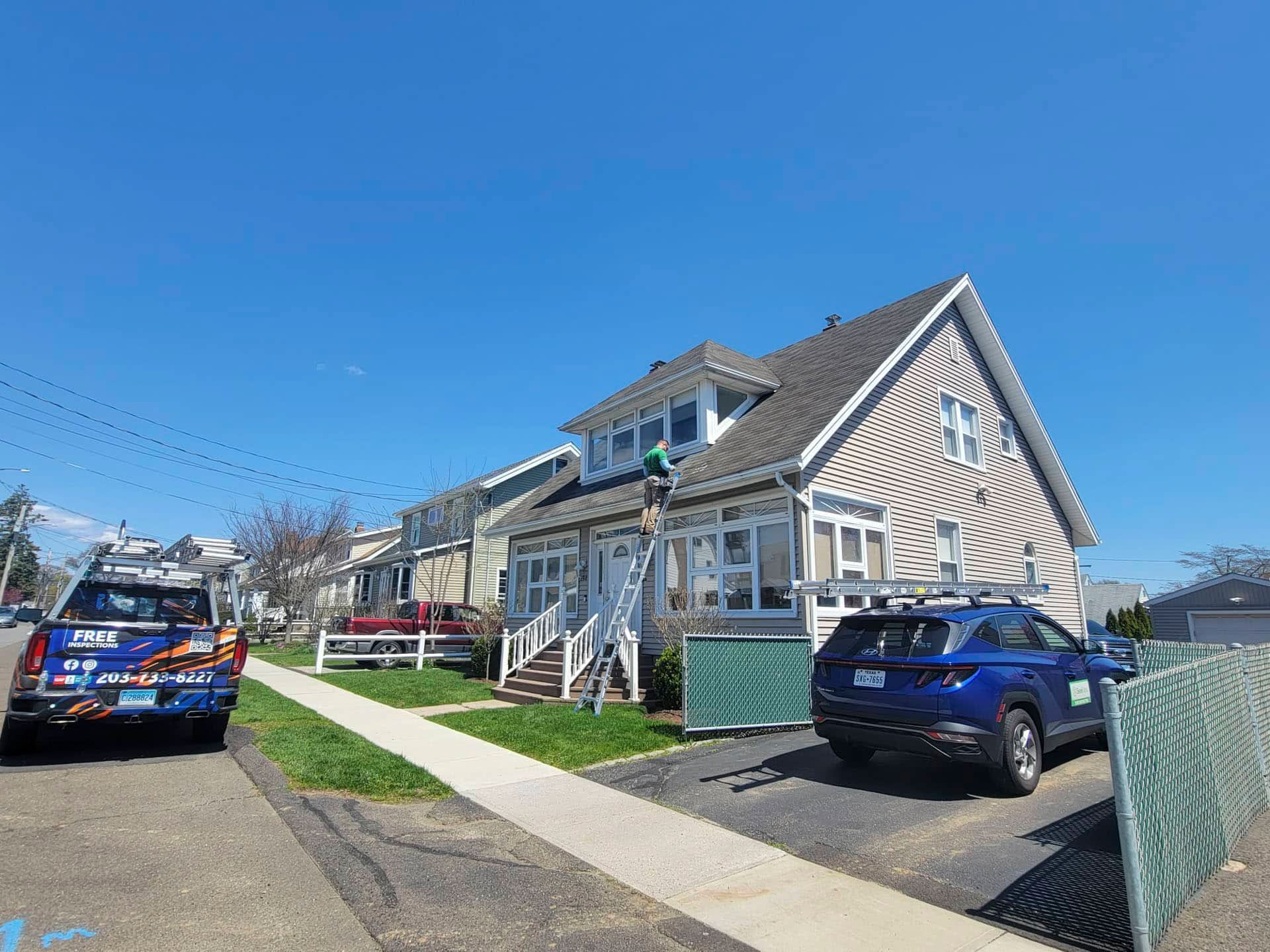 Blue house with striped siding, parked cars, and a sidewalk under a clear blue sky.