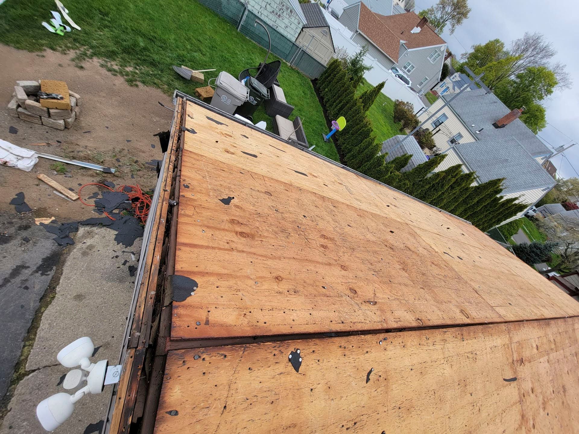 Wooden roof under construction on a house, viewed from above with a backyard and nearby homes in the background