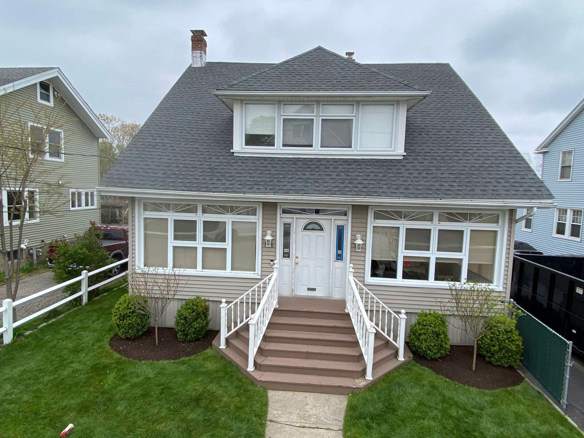 Front view of a gray house with white trim, central steps, and a small front lawn