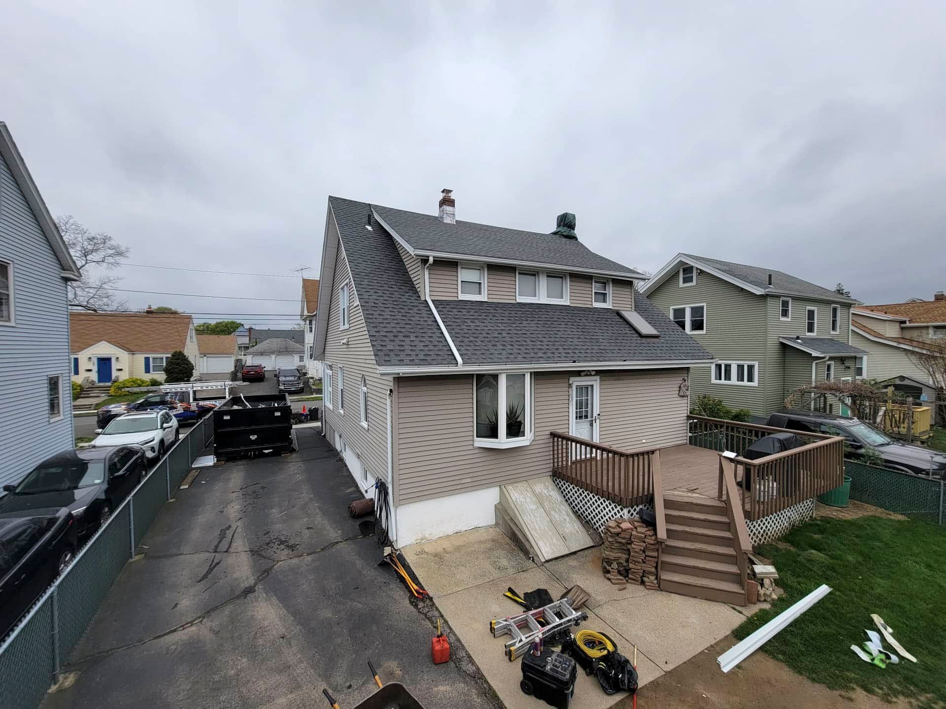 Suburban house with steep roof, driveway, parked SUV, and construction materials in front yard