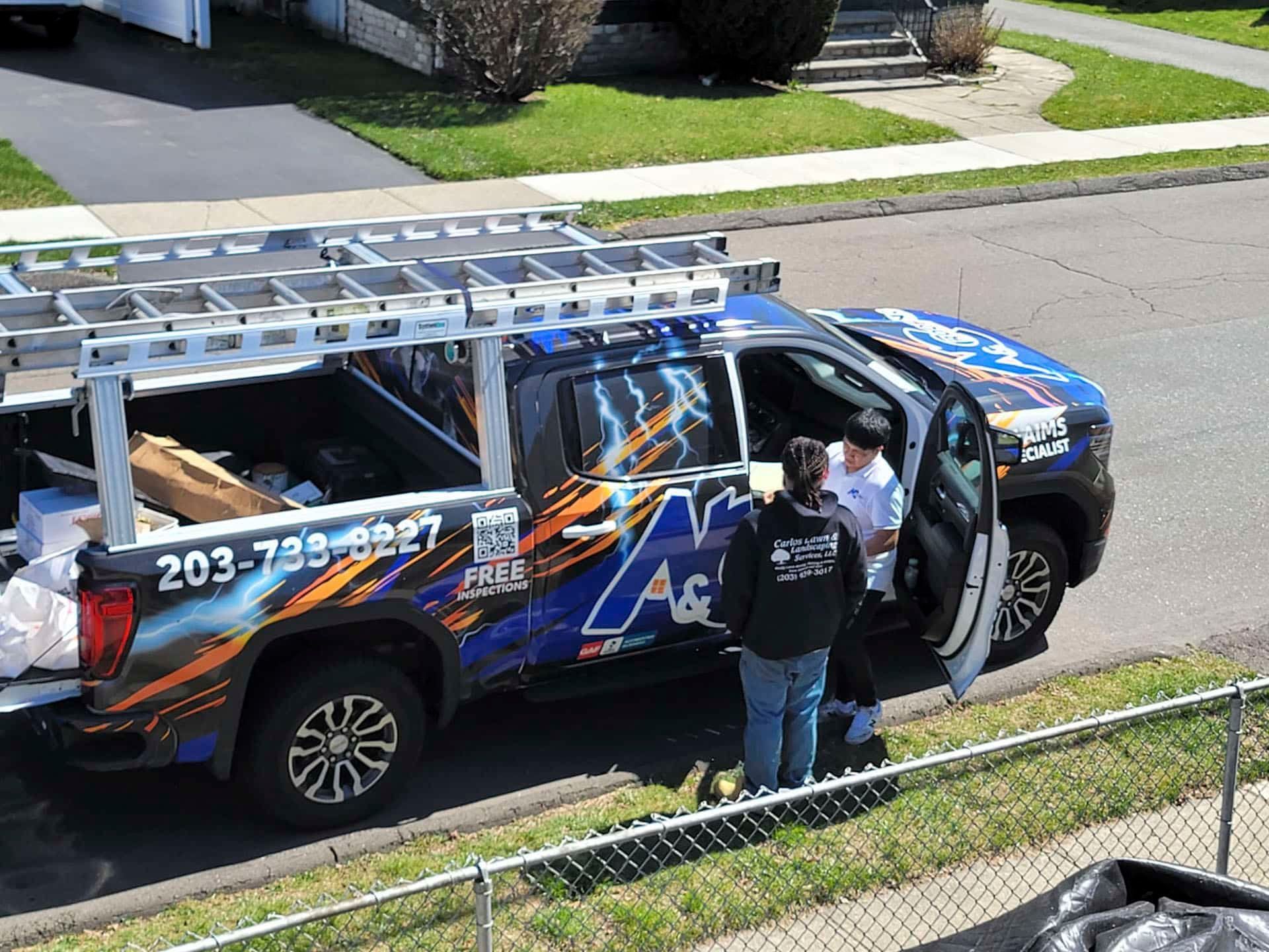 Decorated utility truck parked on a residential street, with two workers standing beside the open door.