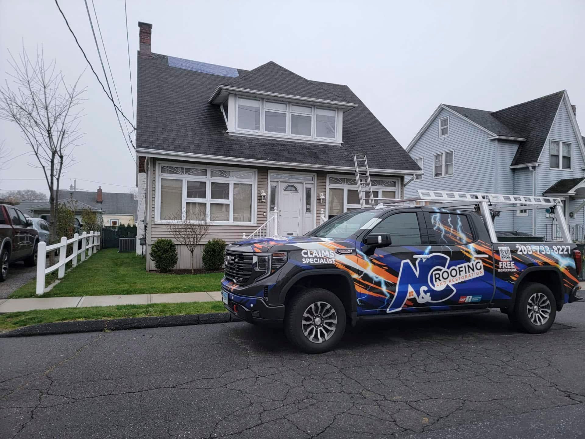 Decorated black SUV parked in front of a gray house on a suburban street