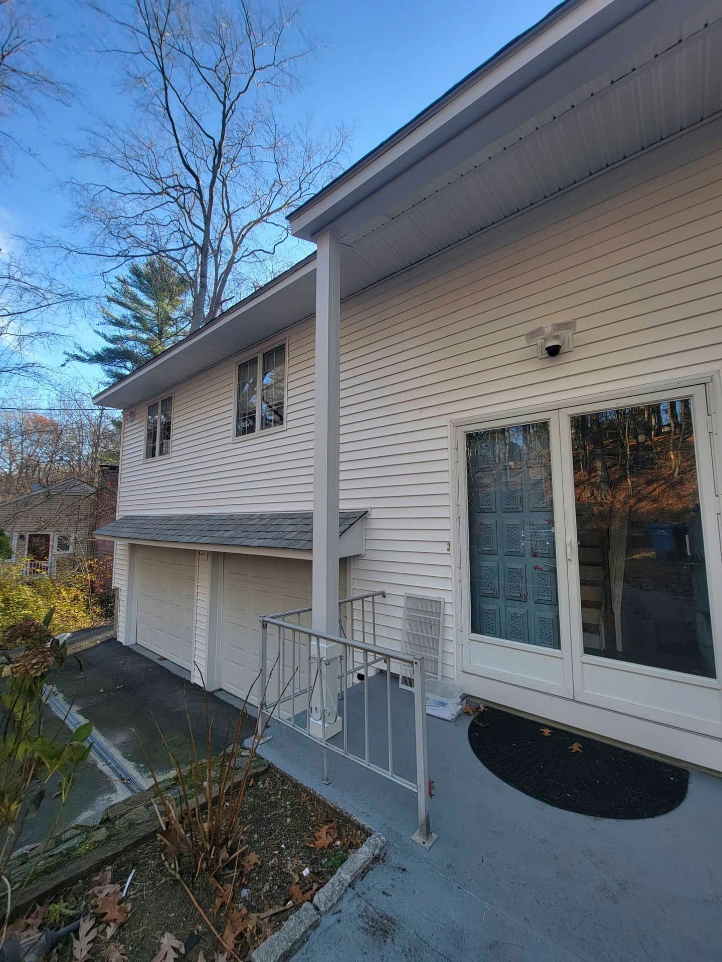 Exterior of a white townhouse with garage, front entry, and concrete walkway on a sunny day
