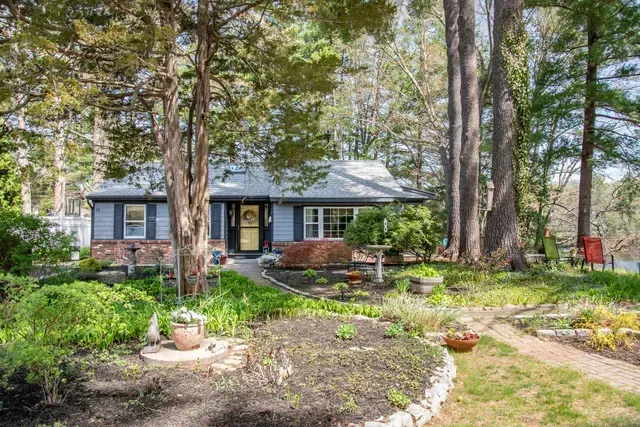 Blue house with garden, trees, and a walkway leading to the front door.