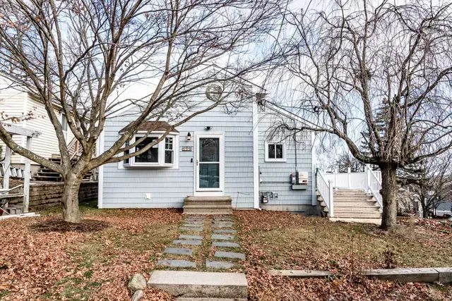 Small blue house with bare trees in front; stone path leads to the door.