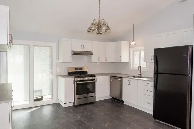 White kitchen with stainless steel appliances, black refrigerator, and glass door.