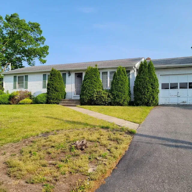 A white house with a gray roof and a driveway
