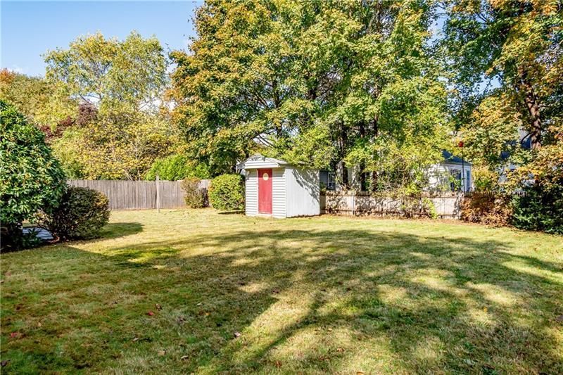 Grassy backyard with shed, trees, and wooden fence.