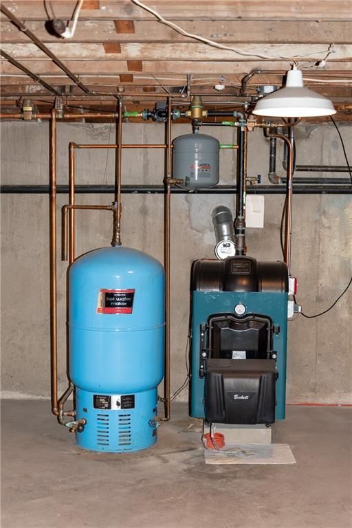Blue water tank and boiler in a basement, connected by copper pipes.