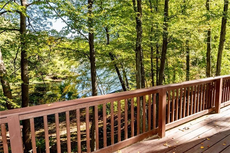 Wooden deck overlooking a lake, surrounded by trees.