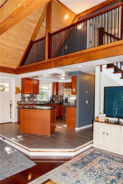 Interior of a home with a kitchen, loft, and living area. Brown wood, gray tile, and blue accents.