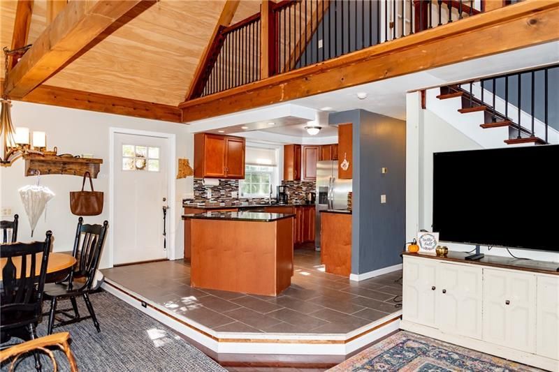 Interior with kitchen, dining area, and living room. Exposed beams, stairs to a loft.