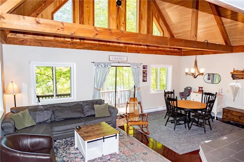 Living room with a gray sectional, wooden beams, a dining table, and a sliding glass door.
