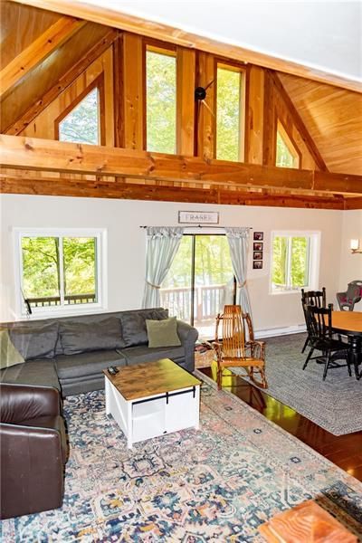 Living room with wooden beams and high ceilings, sectional sofa, rug, and dining area.