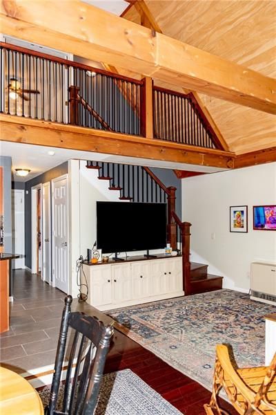 Interior living space with a loft, wood beams, and stairs leading to an upper level.