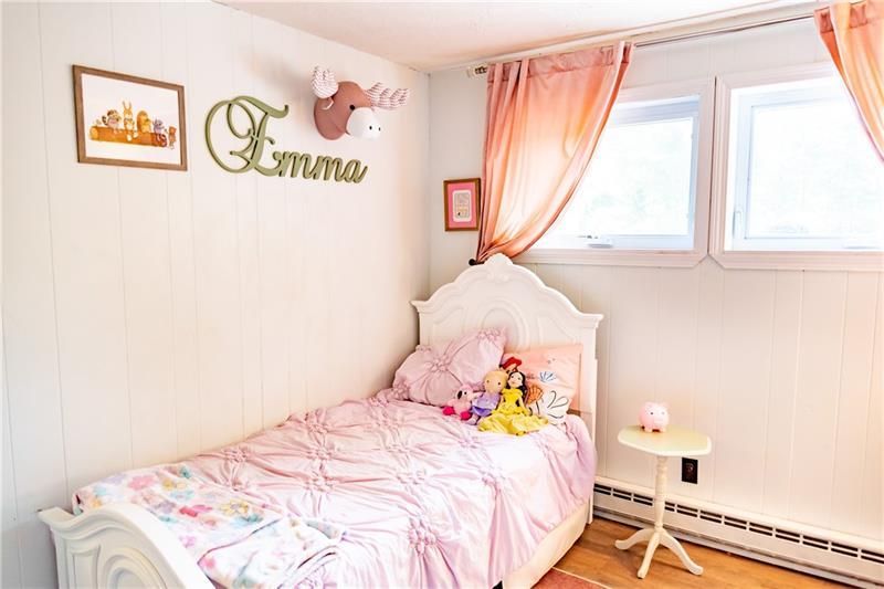 Girl's pink bedroom with bed, artwork, and curtains. Decorative deer head and name