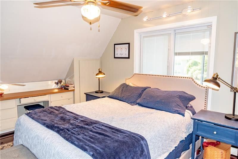 Bedroom with bed, nightstands, window, and built-in desk. Neutral walls, blue accents, natural light.
