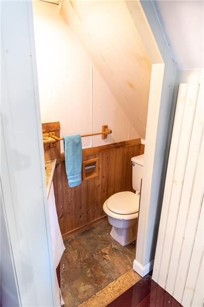 Small bathroom with a toilet, wood paneling, and a towel rack.