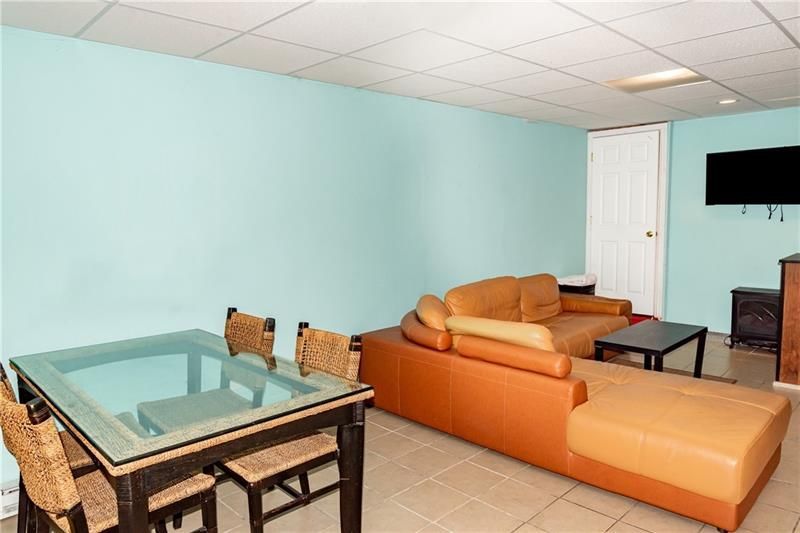Living room with teal walls, a brown leather sectional, a glass-top dining table, and a TV.