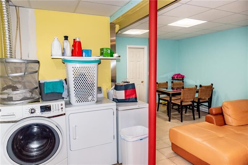 Laundry room with a washer, dryer, and table with chairs in a blue and yellow room.