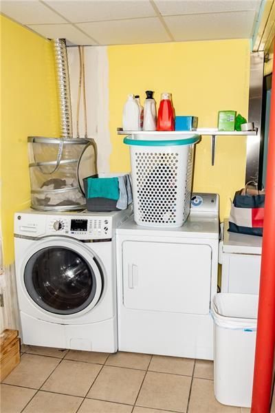 Laundry room with washer, dryer, yellow walls, and cleaning supplies.