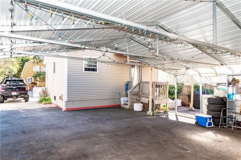 Covered carport attached to a light brown building. A black truck is parked on the left.