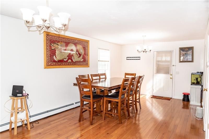 Dining room with wooden table and chairs, tapestry, and hardwood floors.