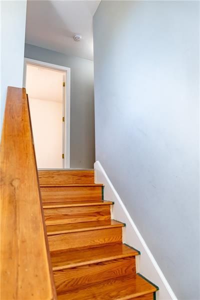 Wooden staircase leading up to an open doorway with light blue walls and a wooden handrail.