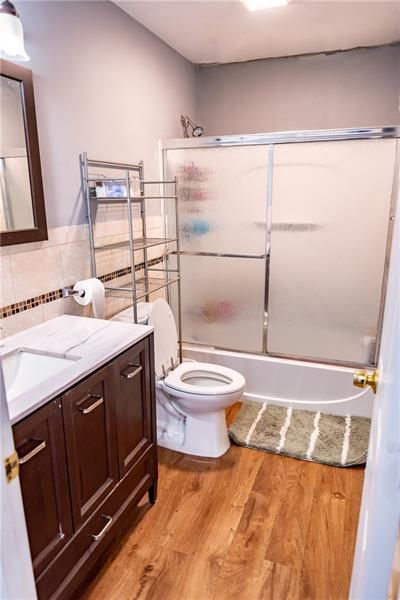 Bathroom with wood-look floor, vanity, toilet, and a shower/tub.  Gray walls, and a towel rack.