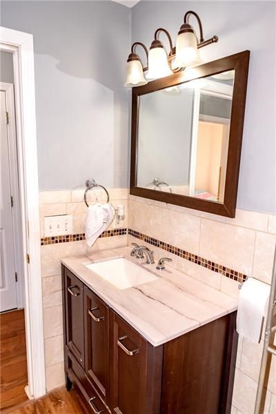 Bathroom with dark wood vanity, white countertop, mirror, and light blue walls.