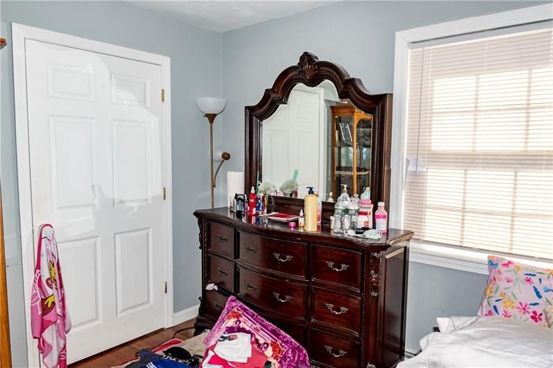 Bedroom with dark wooden dresser, large mirror, and closed door; light blue walls.