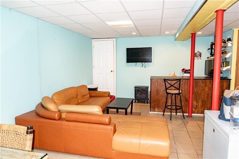 Basement with a brown sectional, bar, TV, and red support beams. Turquoise and beige walls.
