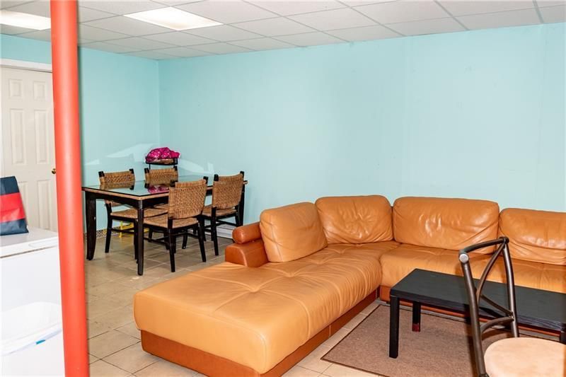 Living room with light blue walls, tan leather sectional, dining table, and red pole.