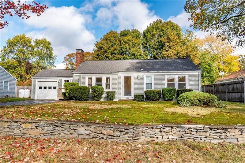 Ranch-style house with gray siding, attached garage, and a lawn with fall foliage.
