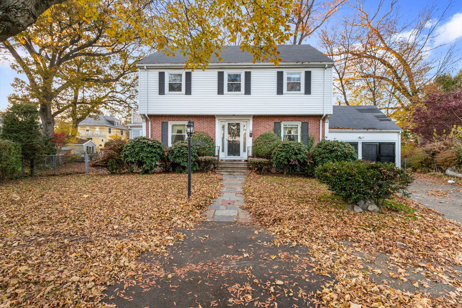 A house with a lot of leaves on the ground in front of it