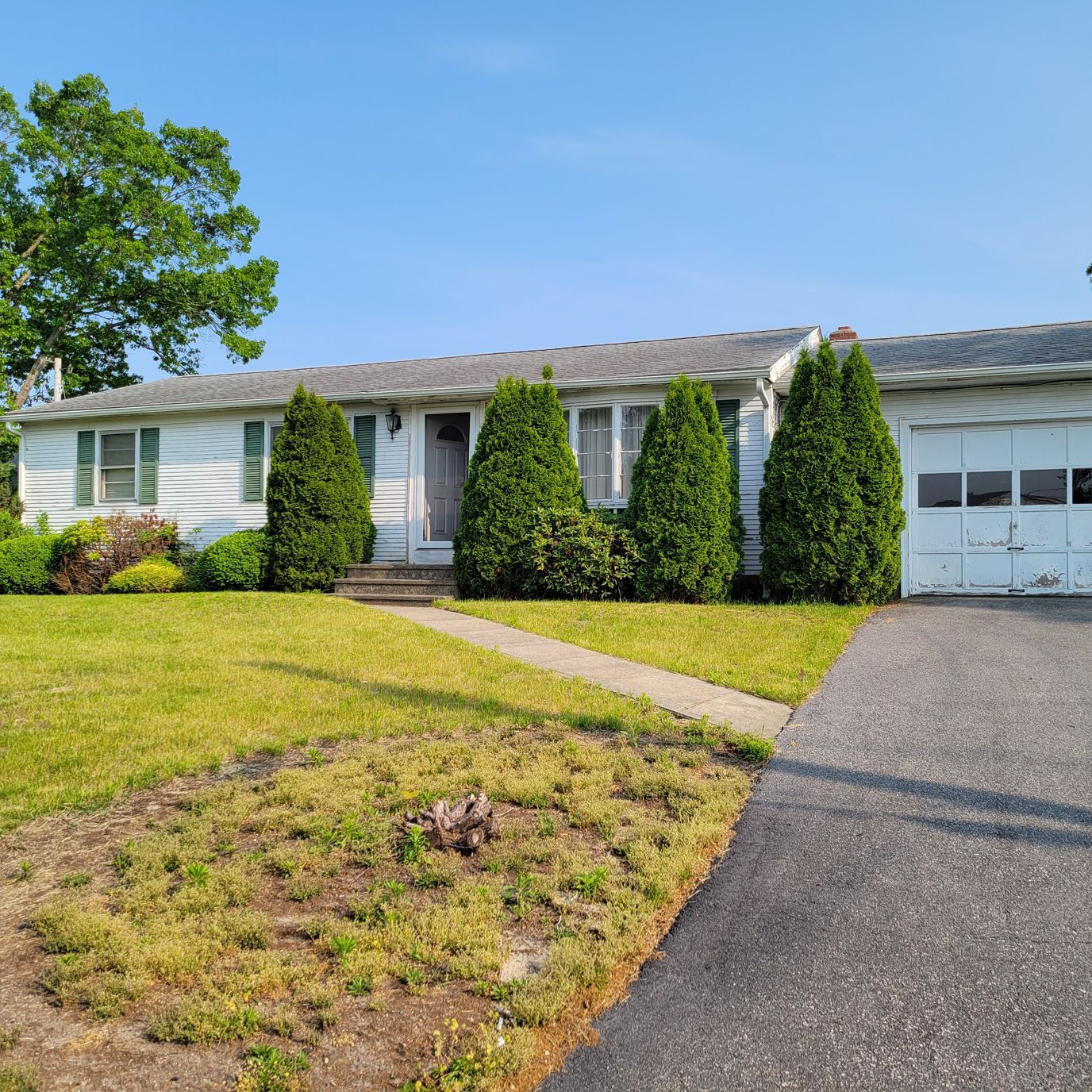A white house with a gray roof and a driveway