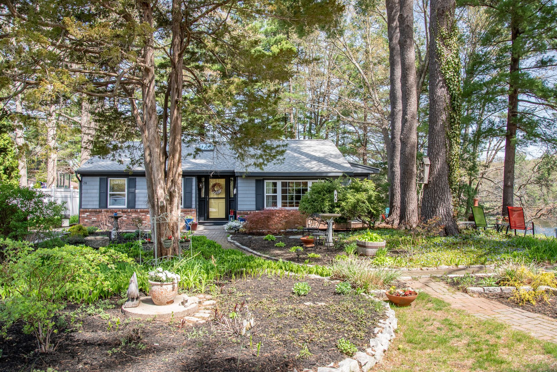 Blue house with garden, trees, and a walkway leading to the front door.