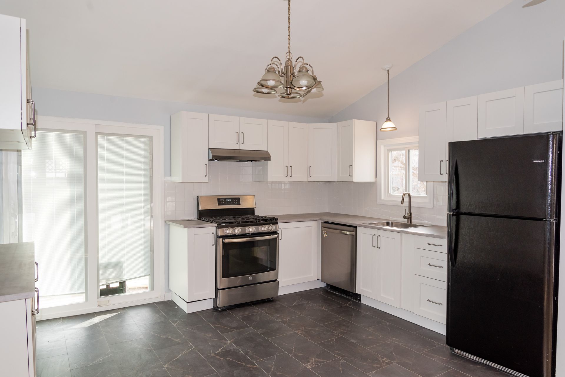 White kitchen with stainless steel appliances, black refrigerator, and glass door.