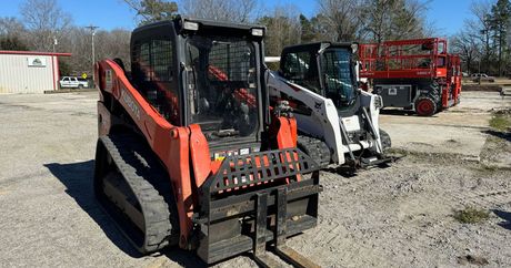 Two bulldozers are parked next to each other in a gravel lot.