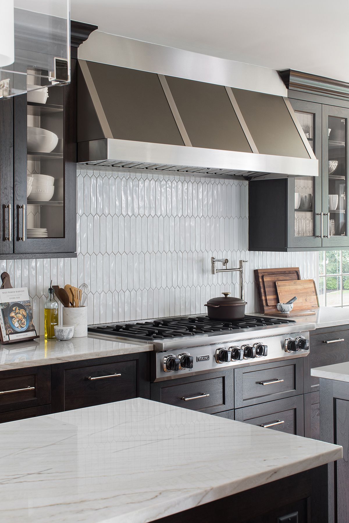Modern kitchen with stainless stove, white tile backsplash, and striped awning over the range hood.