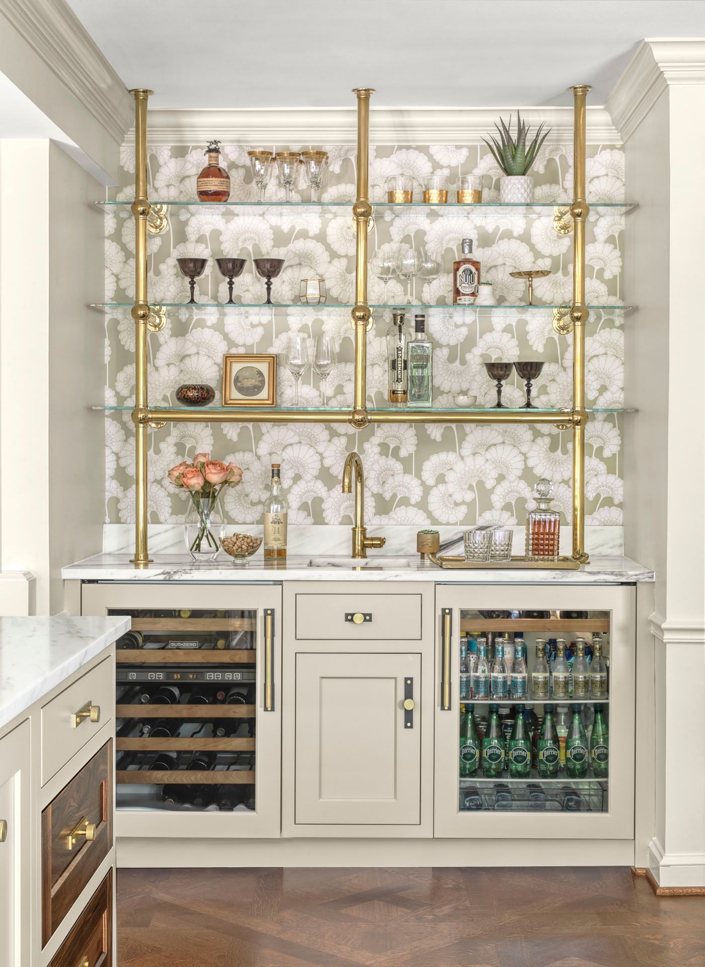 Elegant home bar with gold shelves, glassware, bottles, and a built-in wine fridge.