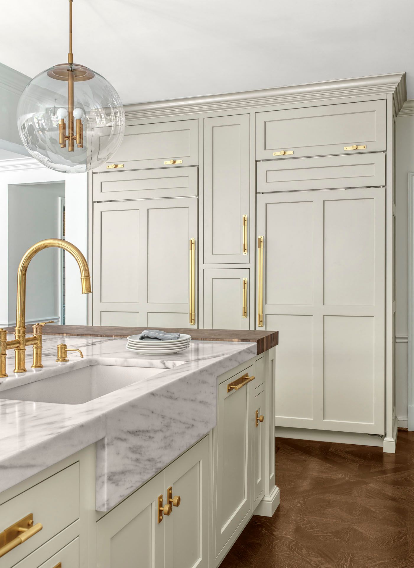 Elegant white kitchen with gold hardware, marble island, and built-in cabinets.
