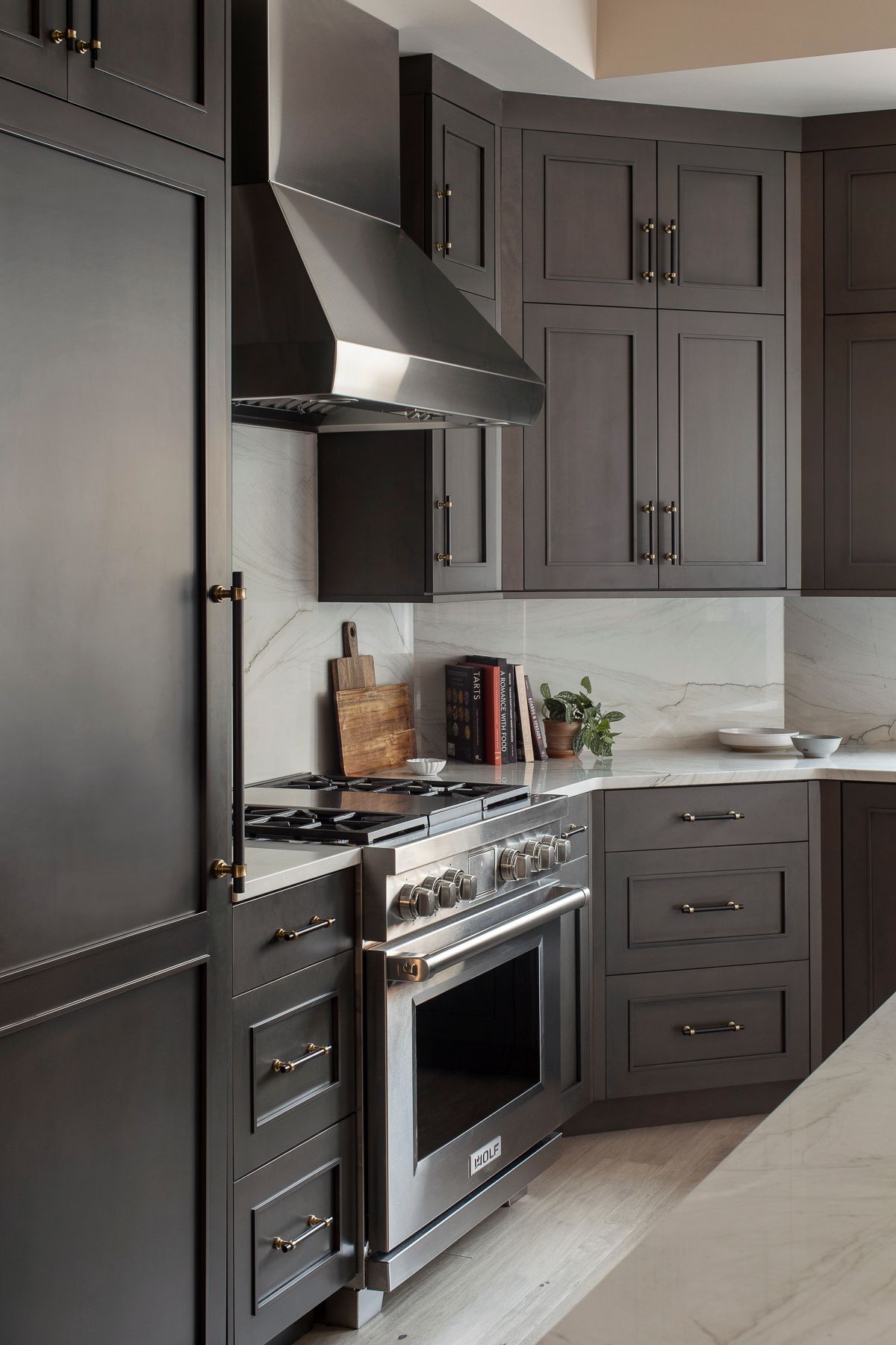 Modern kitchen with dark cabinets, stainless steel stove, and black range hood