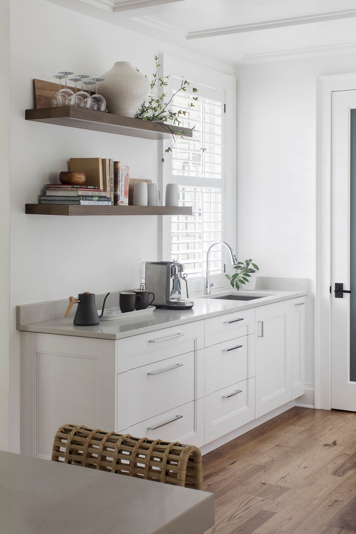 Bright white kitchen with open shelves, countertop appliances, and wood floor.