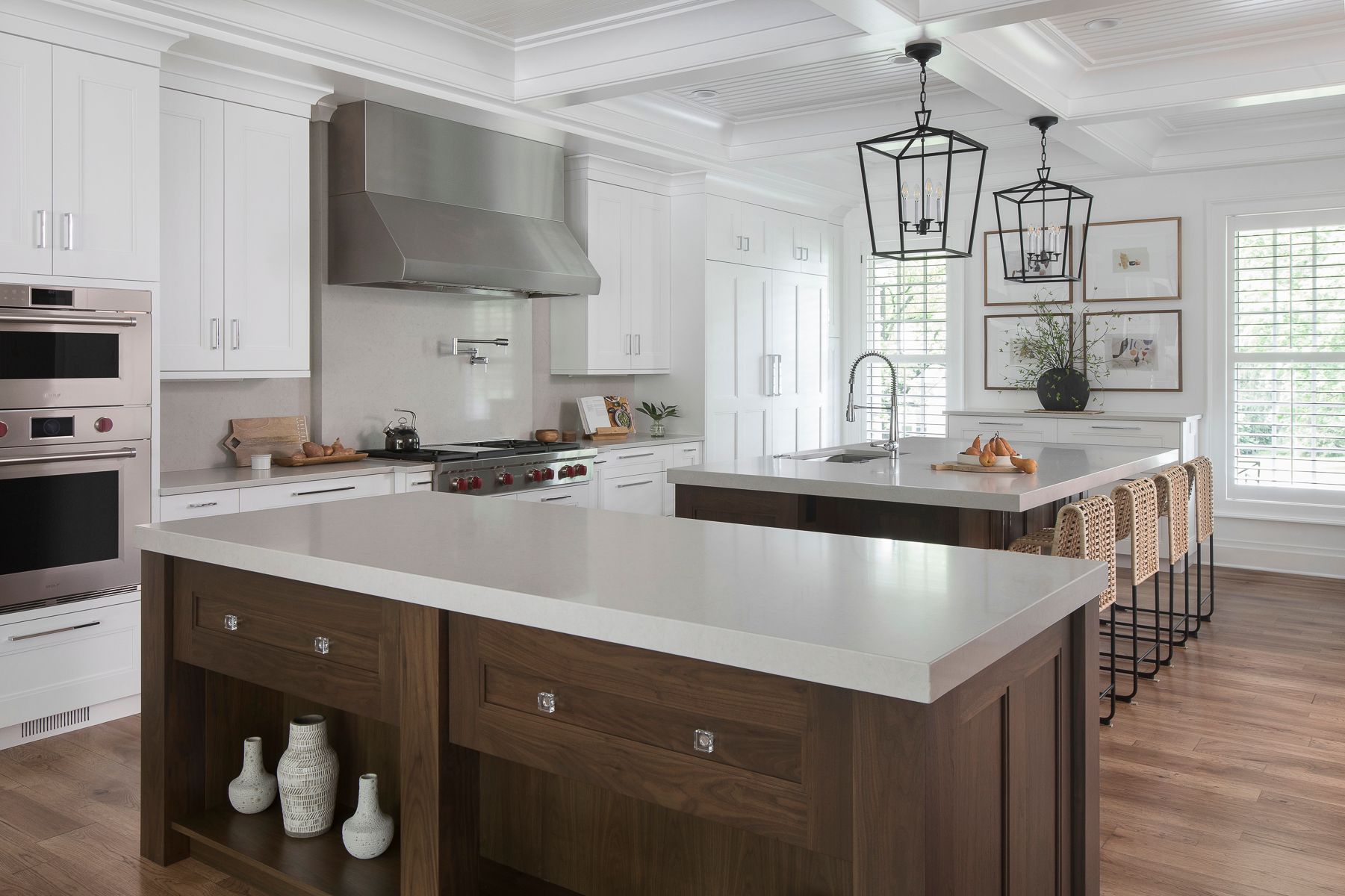 Bright modern kitchen with a large white island, stainless range hood, and wood floors.