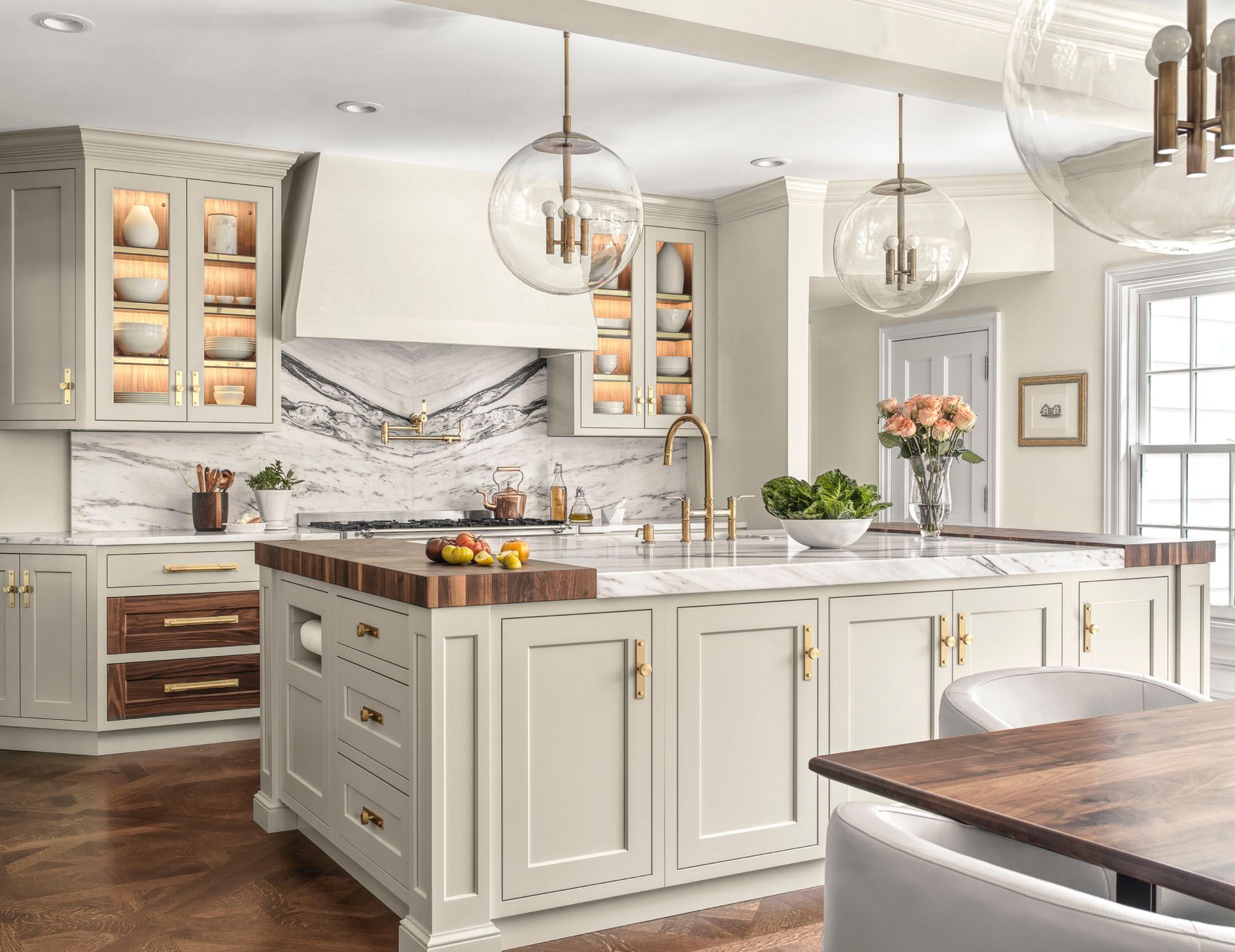 Bright modern kitchen with white cabinets, marble island, wood floors, and pendant lights